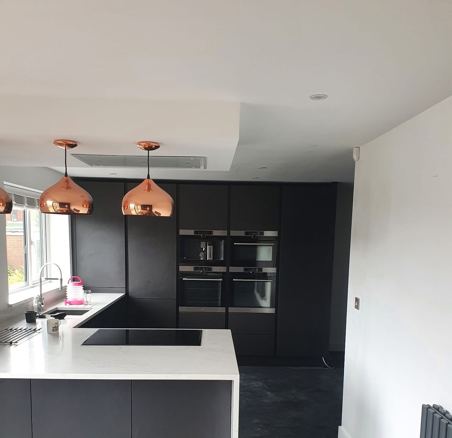 Black handleless kitchen with white worktops fitted in Manchester