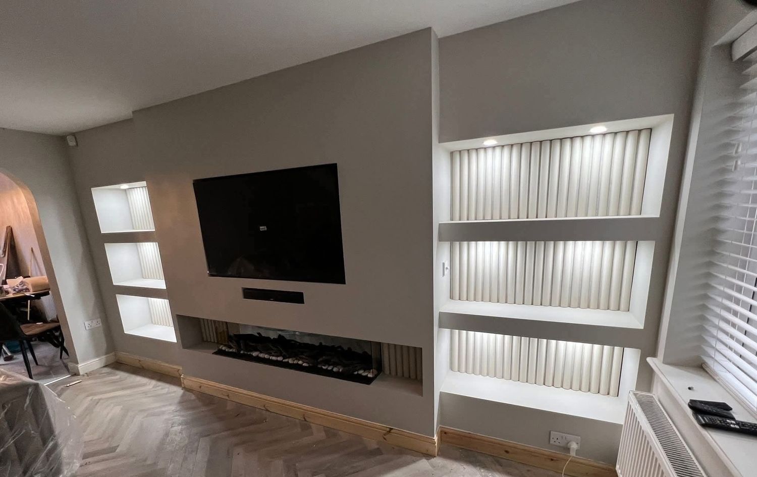 Media wall with built-in fireplace and lit alcoves